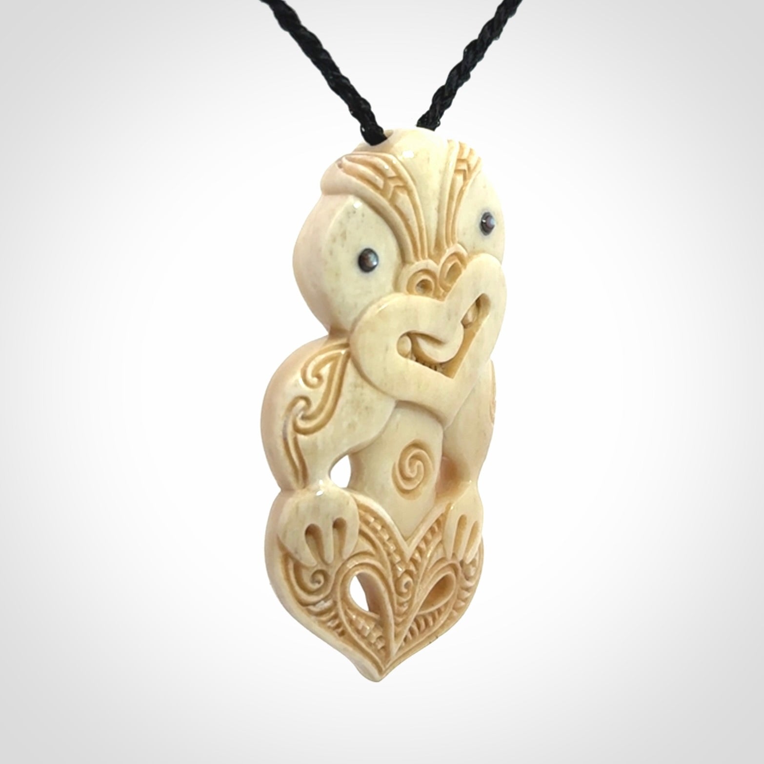 This picture shows a carved Tiki pendant in bone. It is provided with a hand-plaited black cord that is length adjustable.