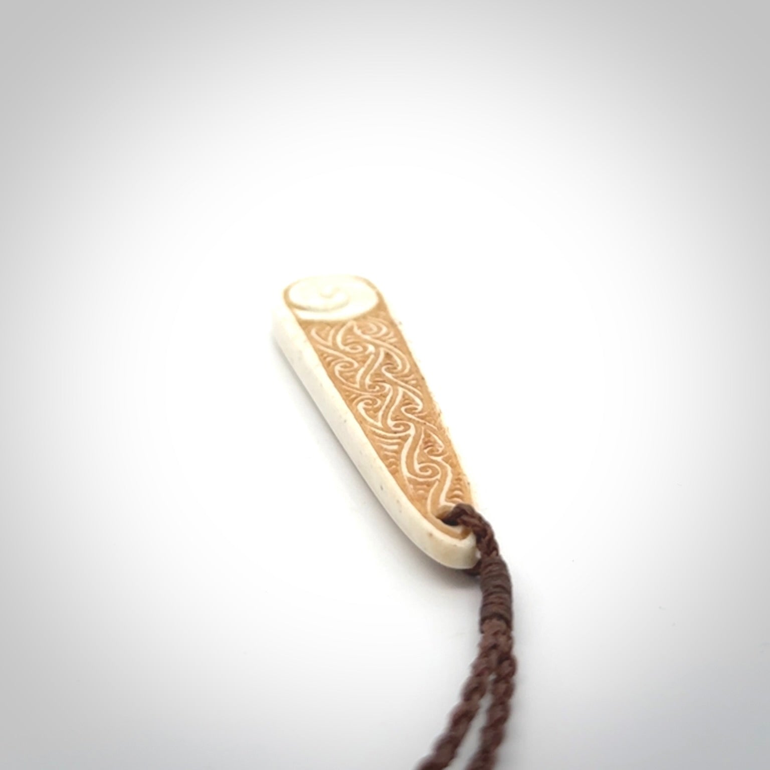 This is a wonderful, finely carved bone drop pendant with paua shell inlay.