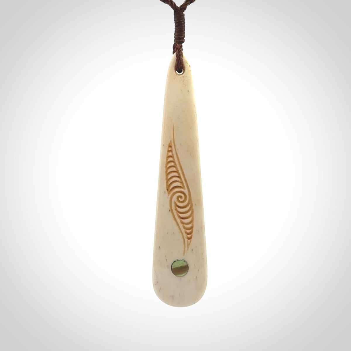 This is a wonderful, finely carved bone drop pendant with paua shell inlay.