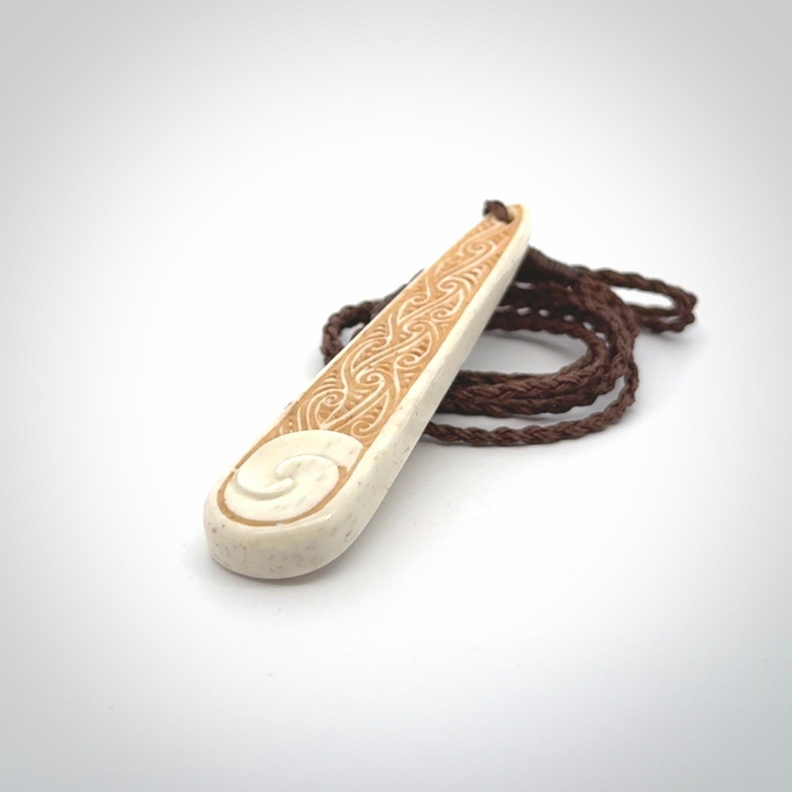 This is a wonderful, finely carved bone drop pendant with paua shell inlay.