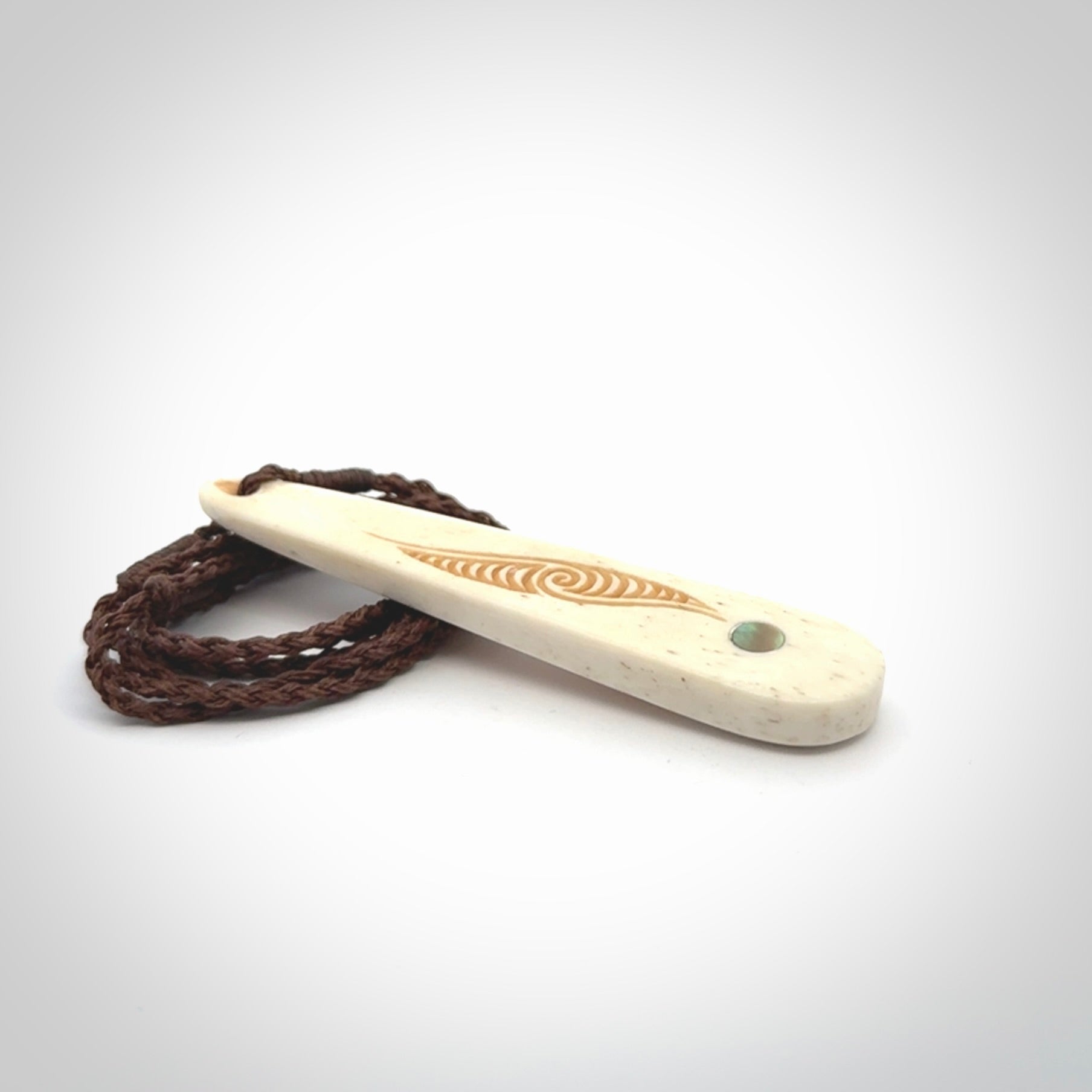 This is a wonderful, finely carved bone drop pendant with paua shell inlay.