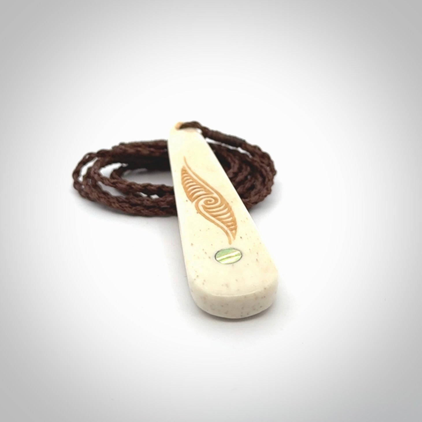 This is a wonderful, finely carved bone drop pendant with paua shell inlay.