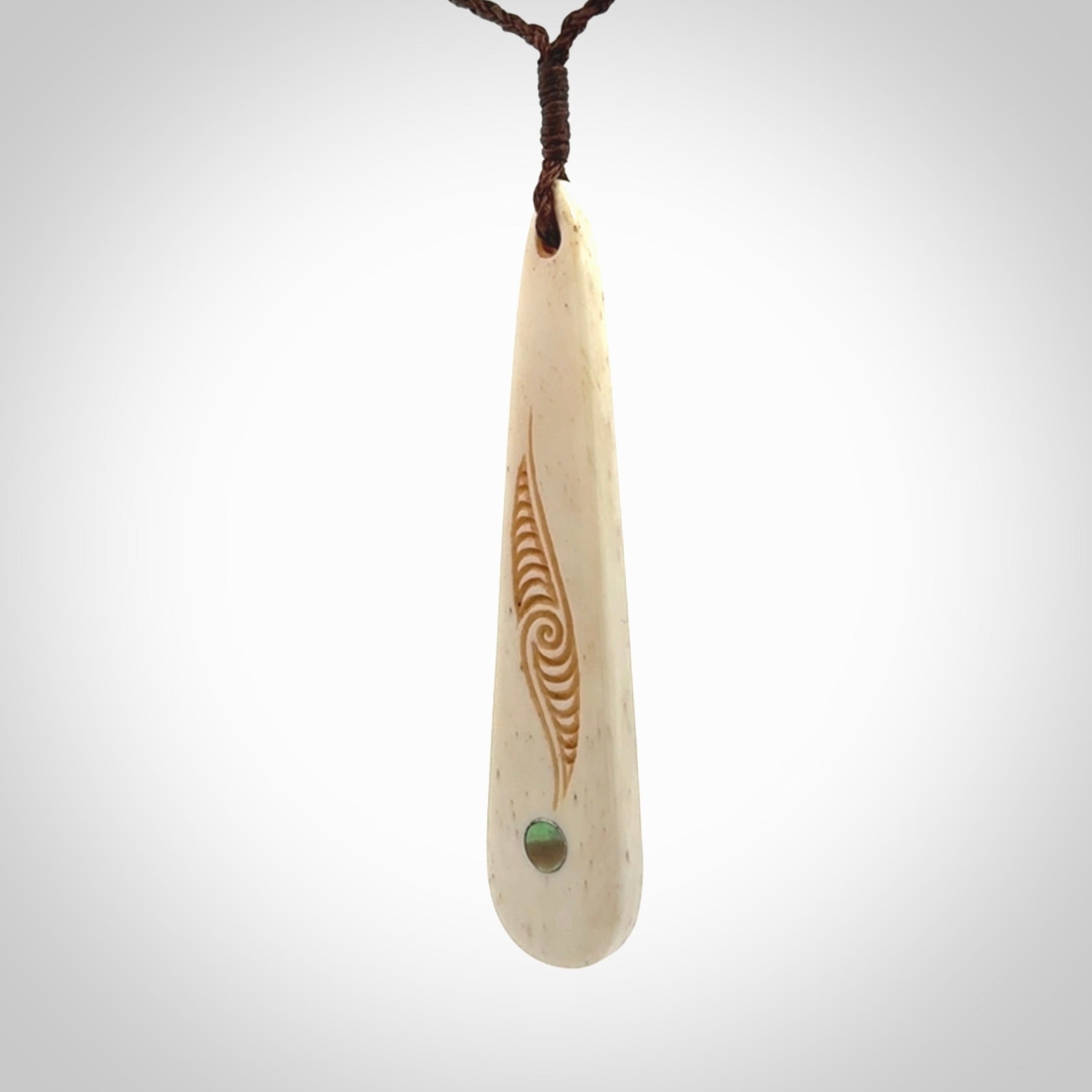 This is a wonderful, finely carved bone drop pendant with paua shell inlay.