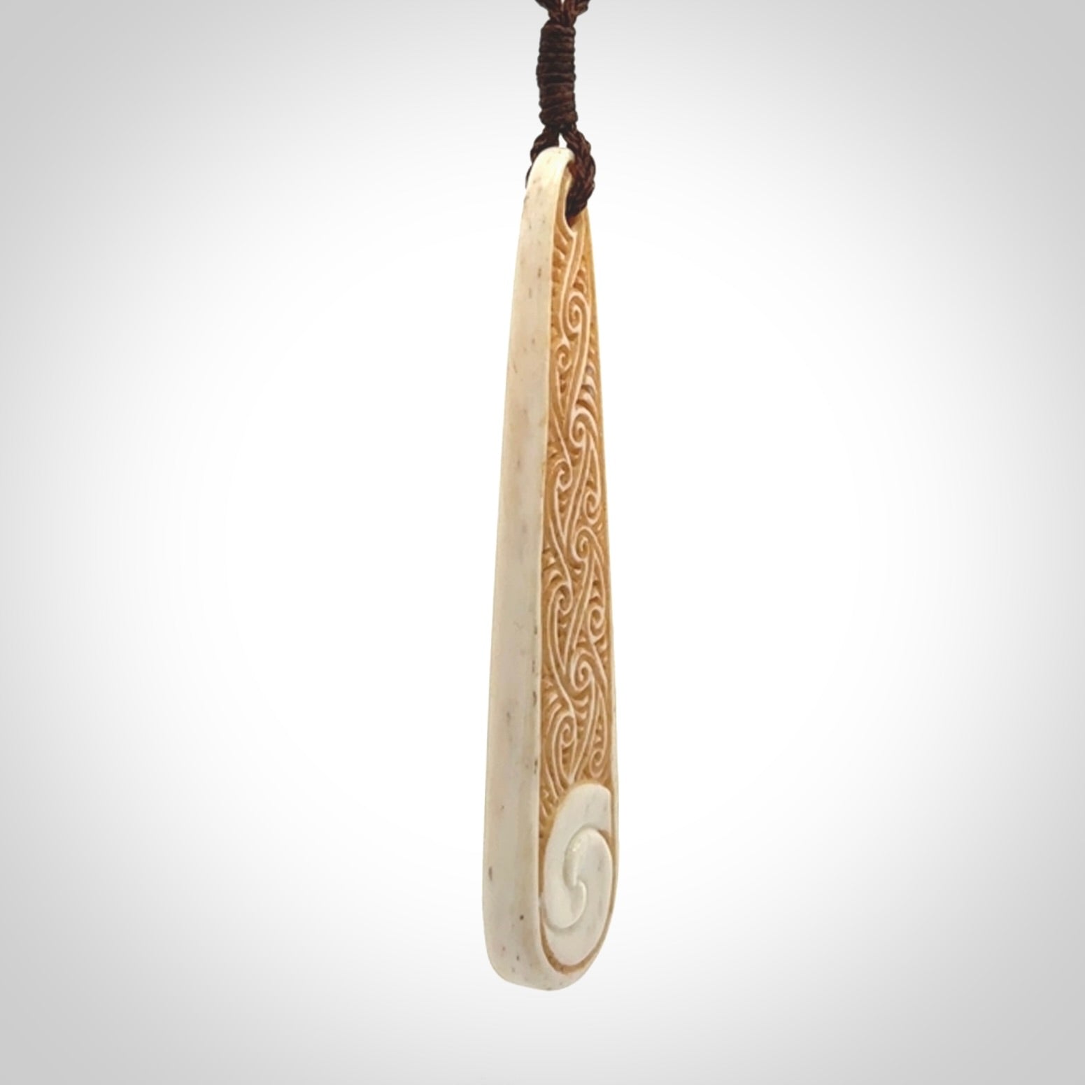 This is a wonderful, finely carved bone drop pendant with paua shell inlay.
