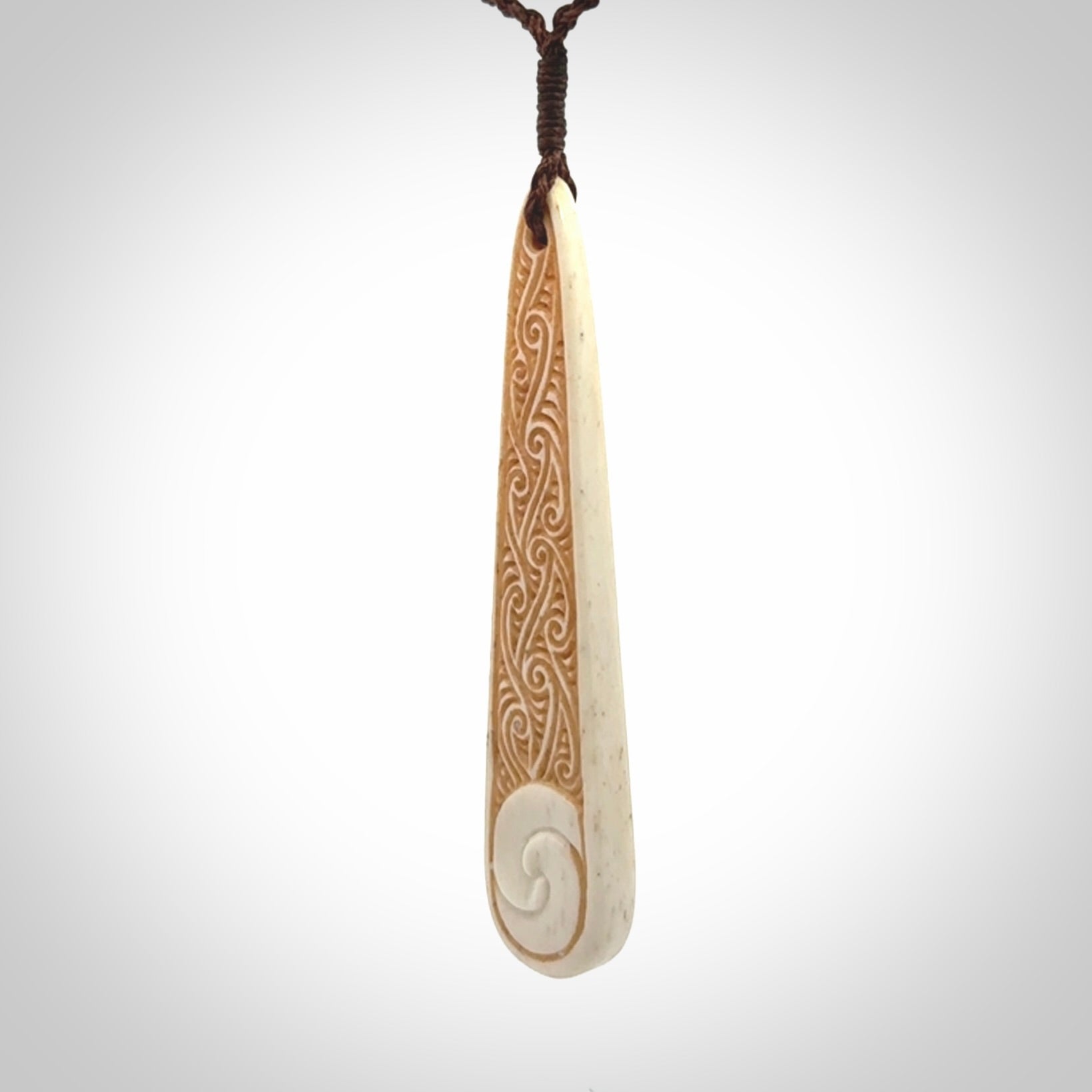 This is a wonderful, finely carved bone drop pendant with paua shell inlay.