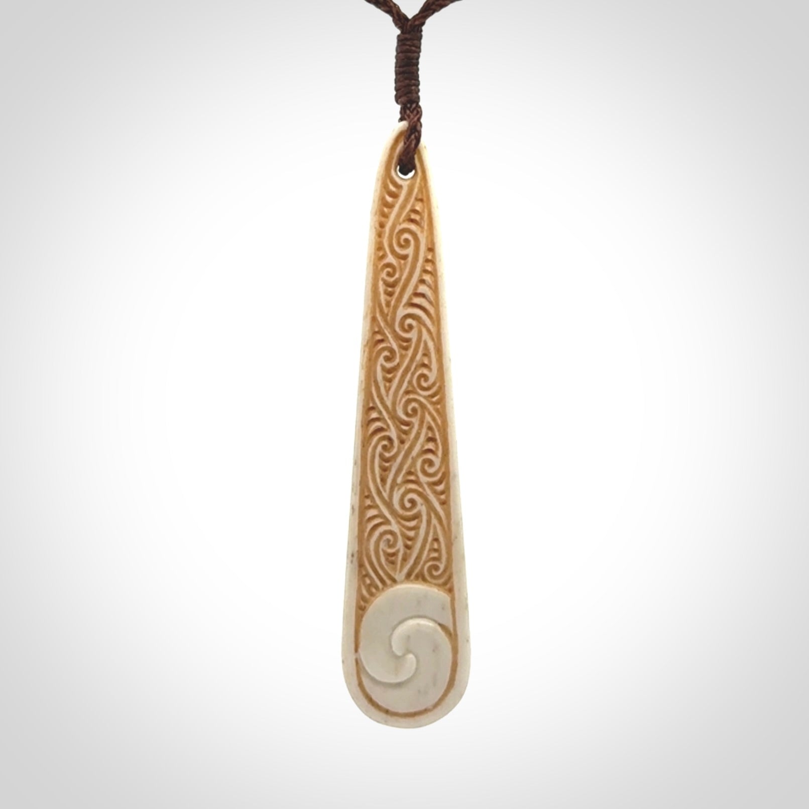 This is a wonderful, finely carved bone drop pendant with paua shell inlay.
