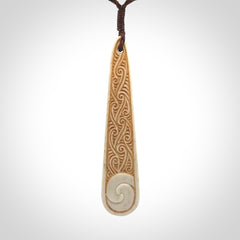 This is a wonderful, finely carved bone drop pendant with paua shell inlay.