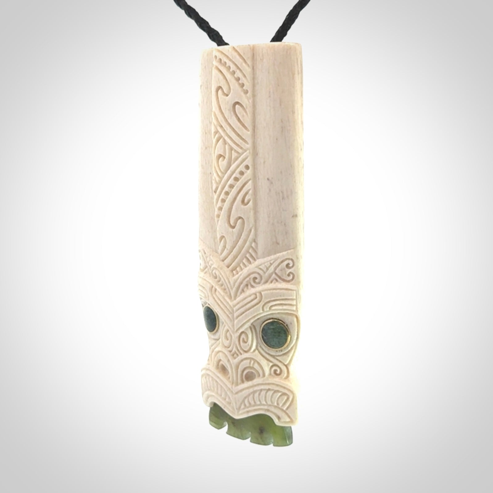 This is a wonderful, finely carved Koruru pendant. It is hand carved by Andrew Doughty and we will ship it to you free anywhere in the world. Hand made from whale bone with Jade, Aotea Stone inlay. Delivered to you with an adjustable black cord.