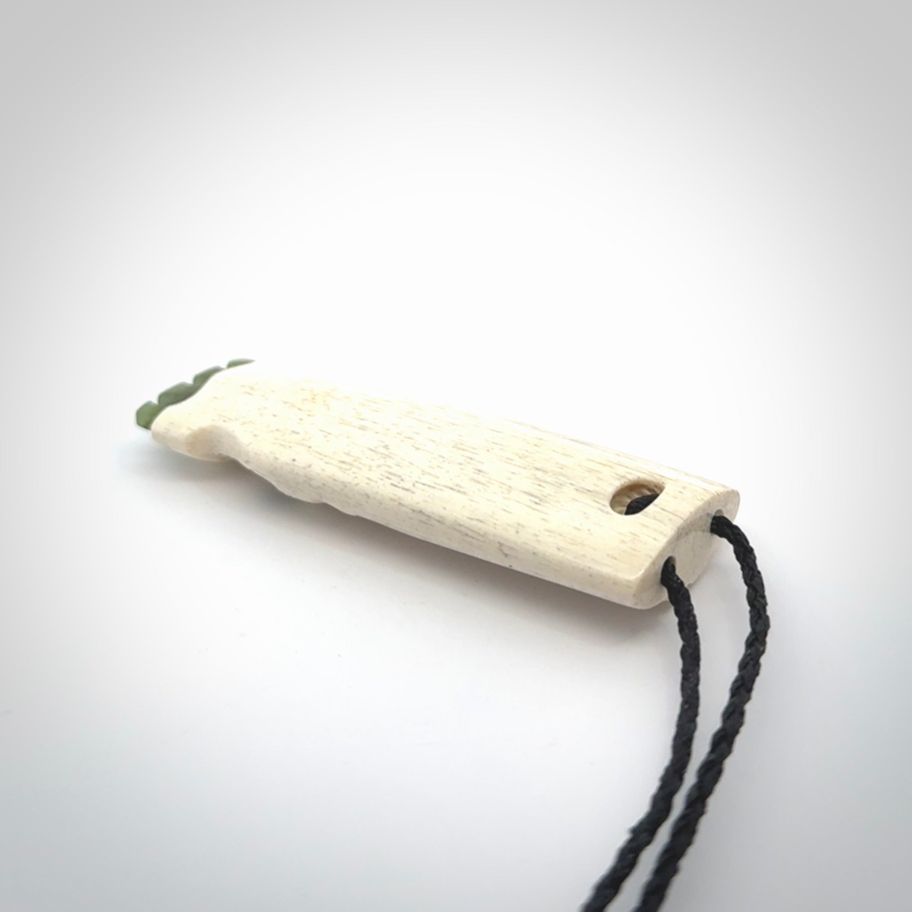 This is a wonderful, finely carved Koruru pendant. It is hand carved by Andrew Doughty and we will ship it to you free anywhere in the world. Hand made from whale bone with Jade, Aotea Stone inlay. Delivered to you with an adjustable black cord.