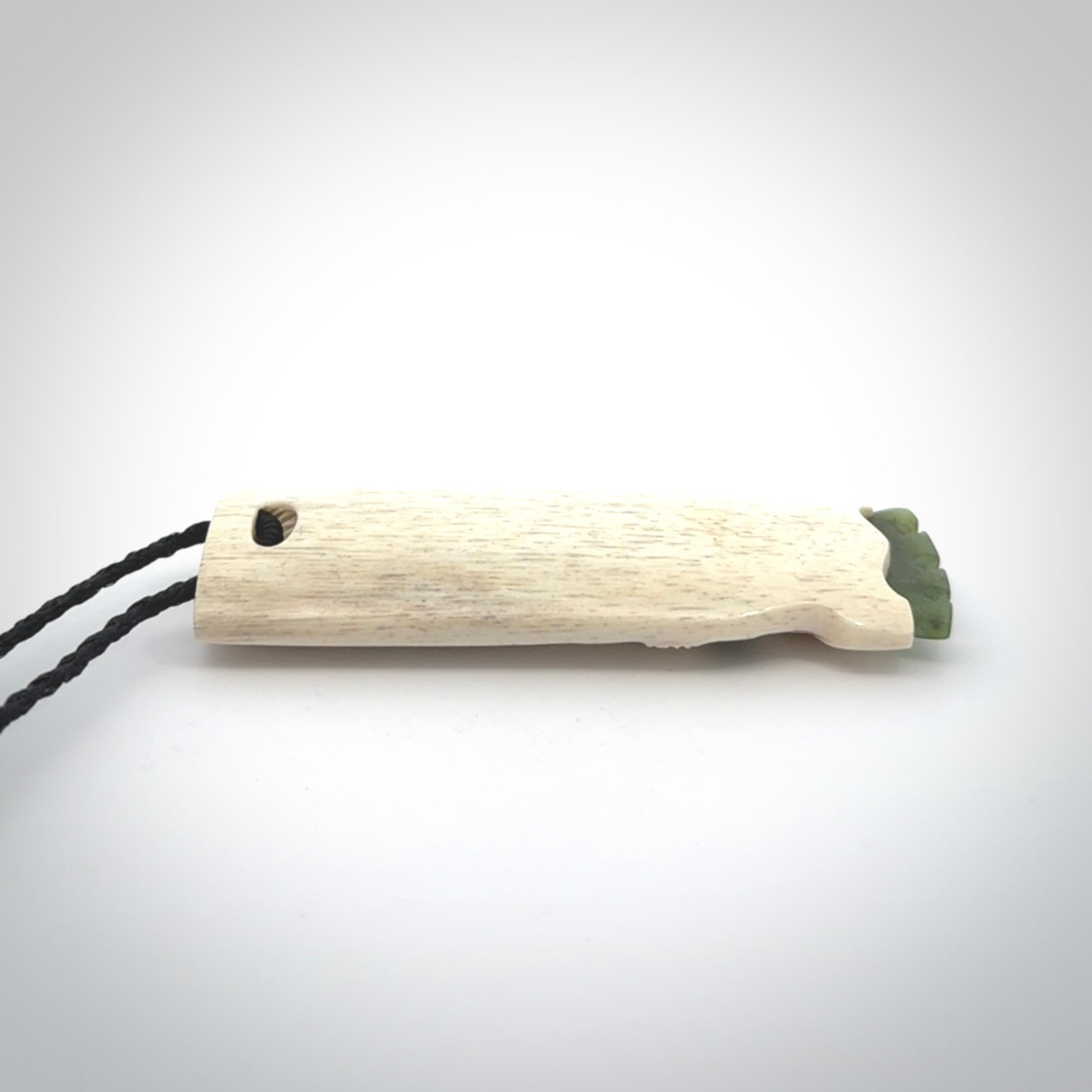 This is a wonderful, finely carved Koruru pendant. It is hand carved by Andrew Doughty and we will ship it to you free anywhere in the world. Hand made from whale bone with Jade, Aotea Stone inlay. Delivered to you with an adjustable black cord.