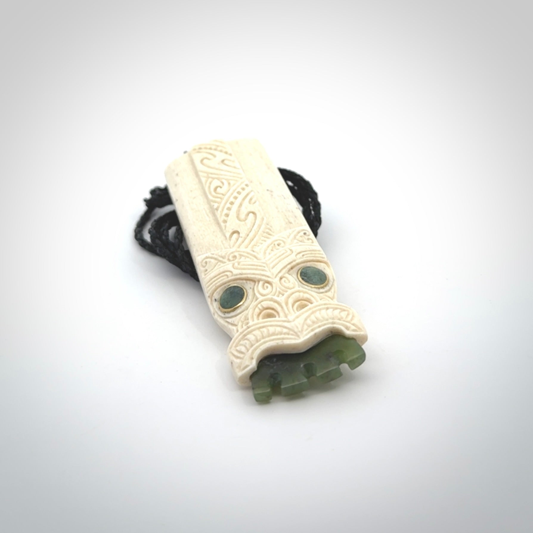 This is a wonderful, finely carved Koruru pendant. It is hand carved by Andrew Doughty and we will ship it to you free anywhere in the world. Hand made from whale bone with Jade, Aotea Stone inlay. Delivered to you with an adjustable black cord.