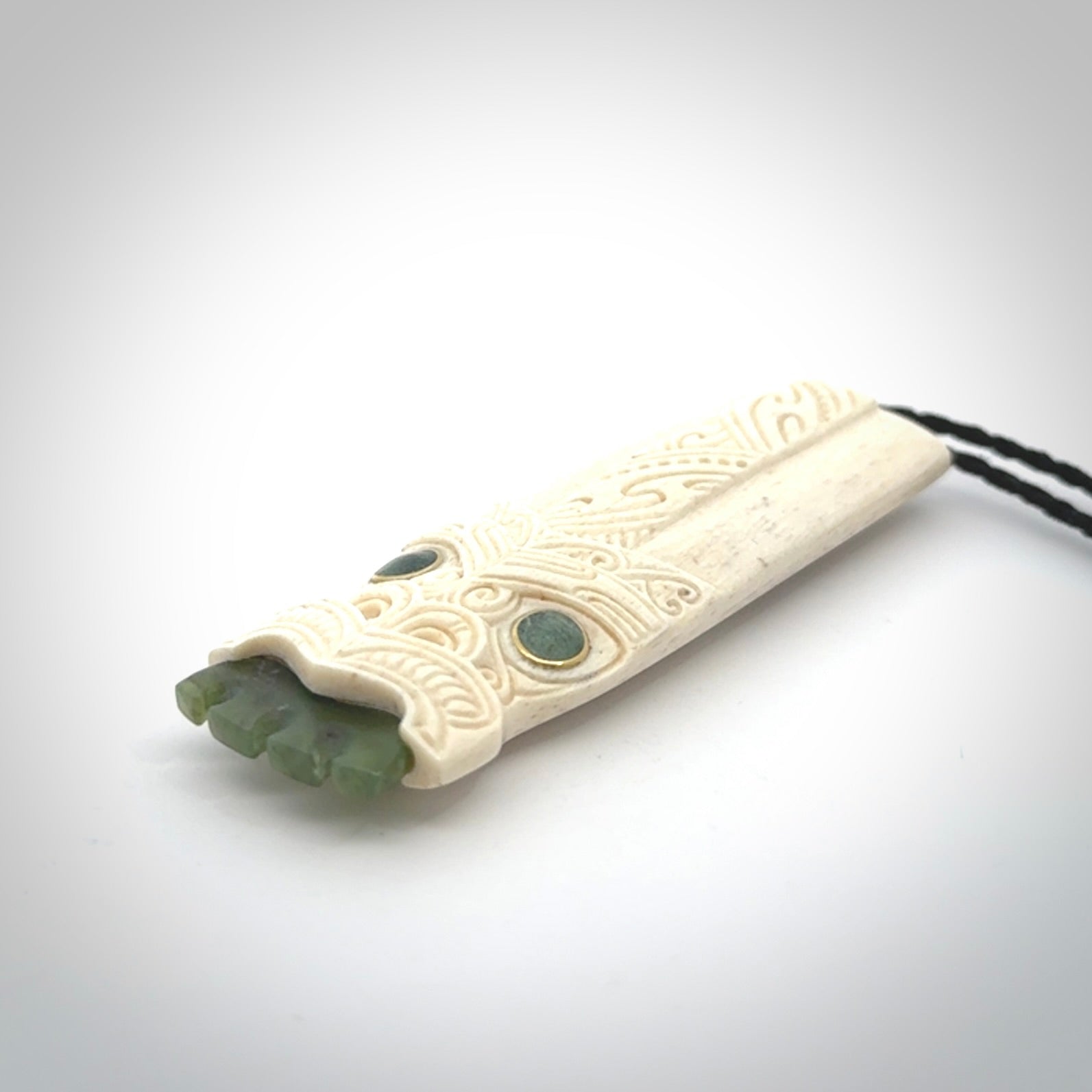 This is a wonderful, finely carved Koruru pendant. It is hand carved by Andrew Doughty and we will ship it to you free anywhere in the world. Hand made from whale bone with Jade, Aotea Stone inlay. Delivered to you with an adjustable black cord.