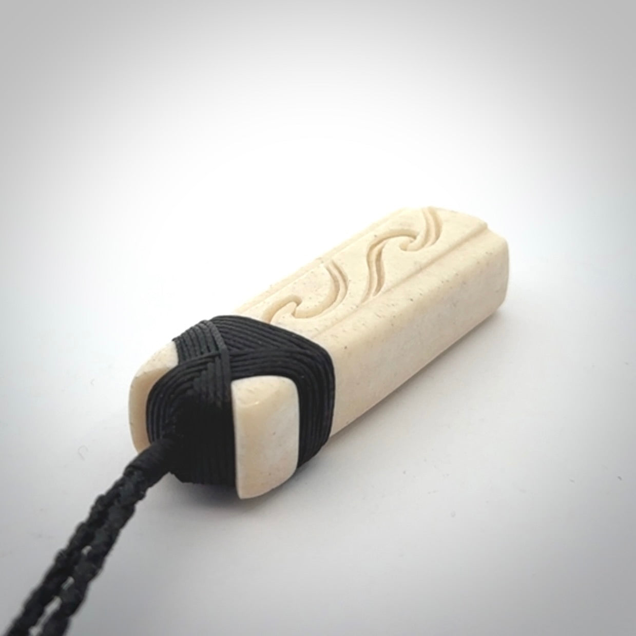 This is a wonderful, finely carved Toki pendant. It is hand carved by Andrew Doughty and we will ship it to you free anywhere in the world. Hand made from whale bone. Delivered to you with an adjustable black cord.