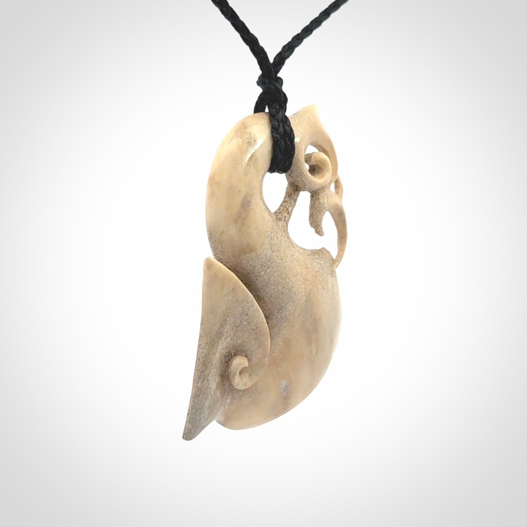 Hand made deer antler manaia pendant. Hand carved by NZ Pacific. Manaia carved from deer antler pendant for sale online. Delivered to you on an adjustable black cord and packaged in a woven kete pouch.