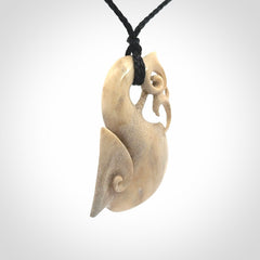 Hand made deer antler manaia pendant. Hand carved by NZ Pacific. Manaia carved from deer antler pendant for sale online. Delivered to you on an adjustable black cord and packaged in a woven kete pouch.