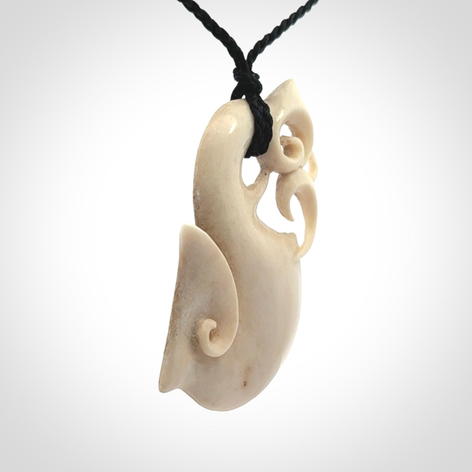 Hand made deer antler manaia pendant. Hand carved by NZ Pacific. Manaia carved from deer antler pendant for sale online. Delivered to you on an adjustable black cord and packaged in a woven kete pouch.