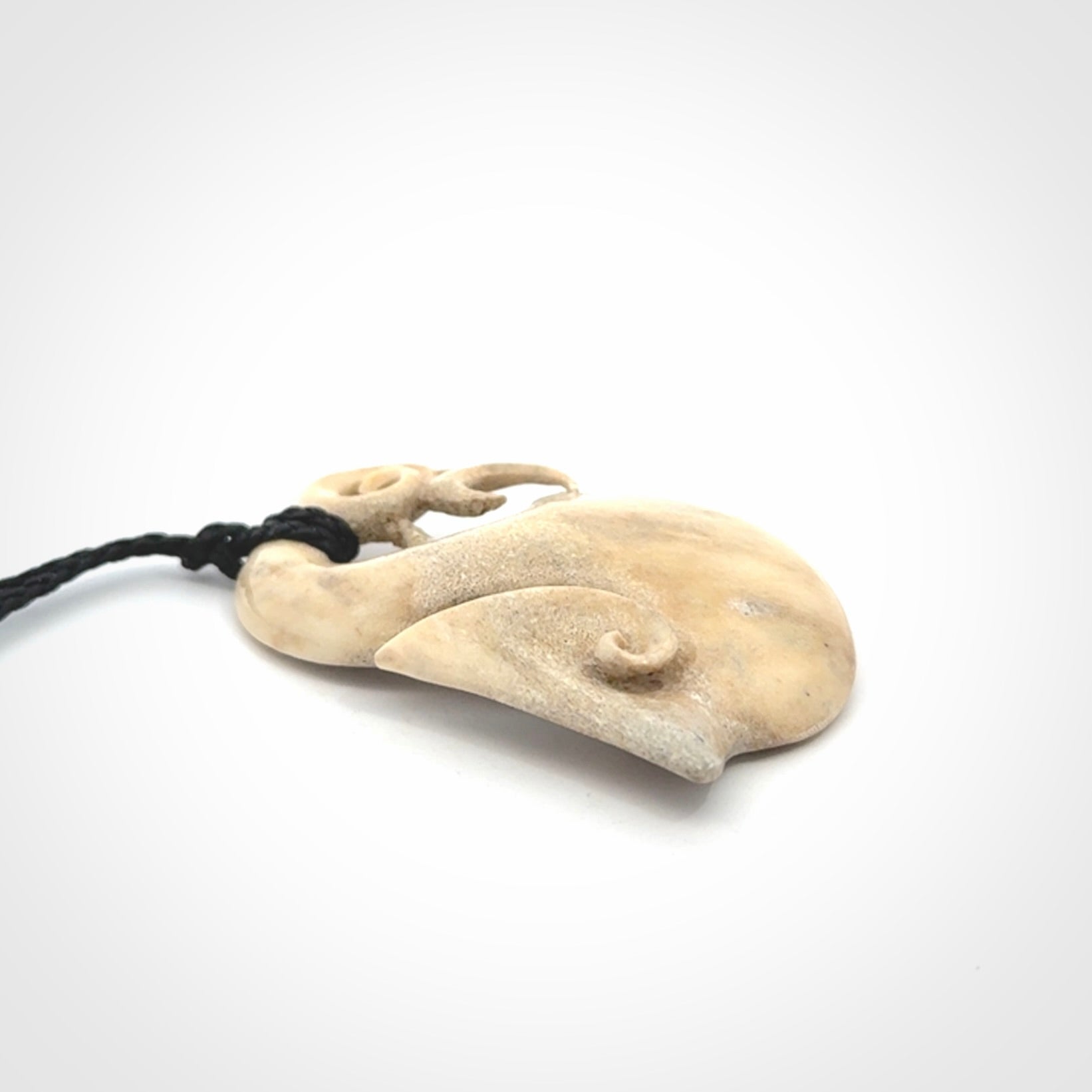 Hand made deer antler manaia pendant. Hand carved by NZ Pacific. Manaia carved from deer antler pendant for sale online. Delivered to you on an adjustable black cord and packaged in a woven kete pouch.