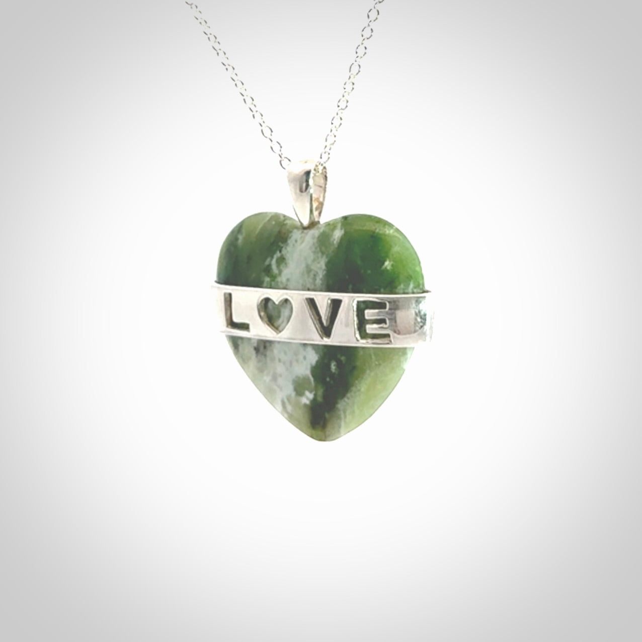 Hand crafted New Zealand jade love heart necklace. This piece has  a sterling silver love written across its' body. This necklace is provided with a sterling silver chain.