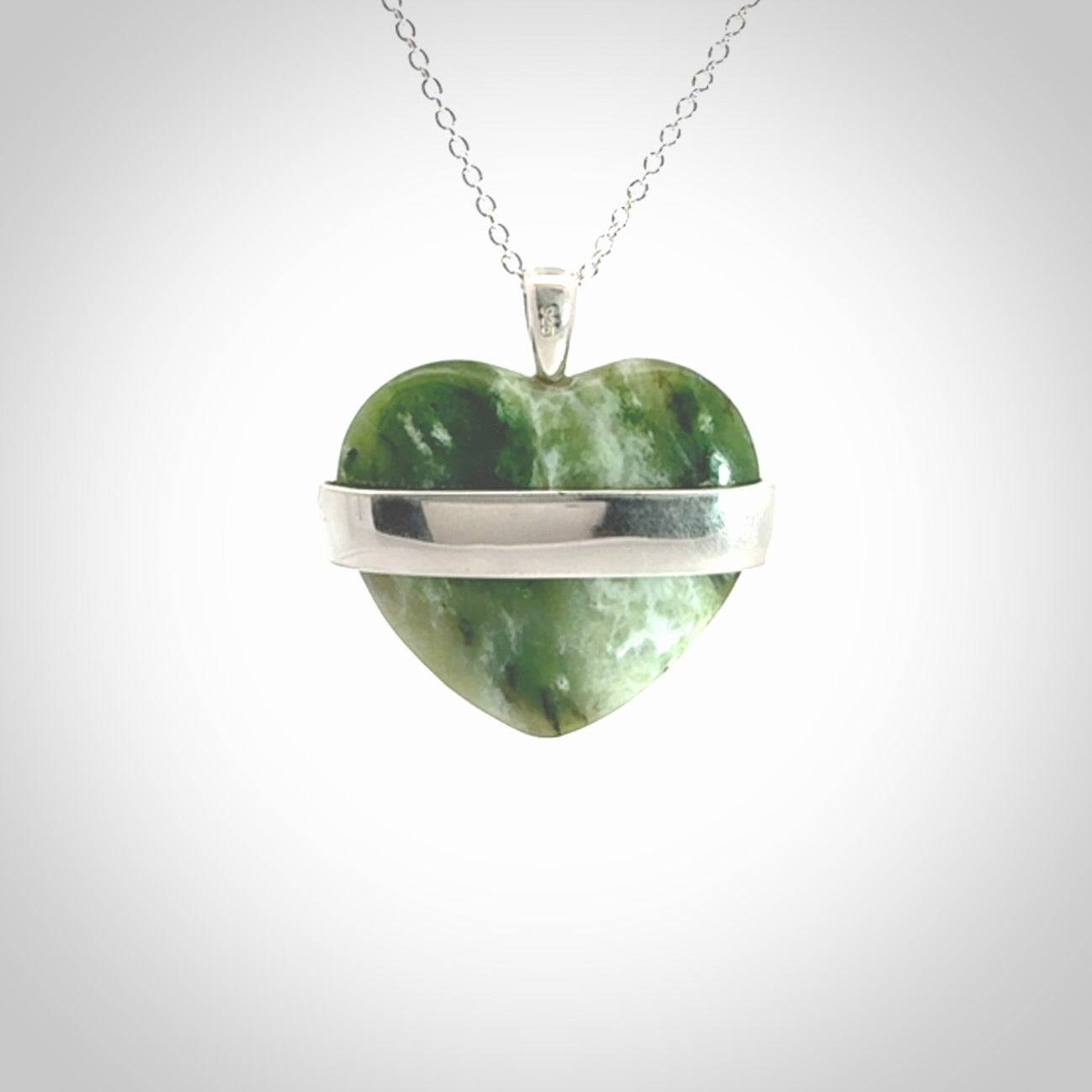 Hand crafted New Zealand jade love heart necklace. This piece has  a sterling silver love written across its' body. This necklace is provided with a sterling silver chain.