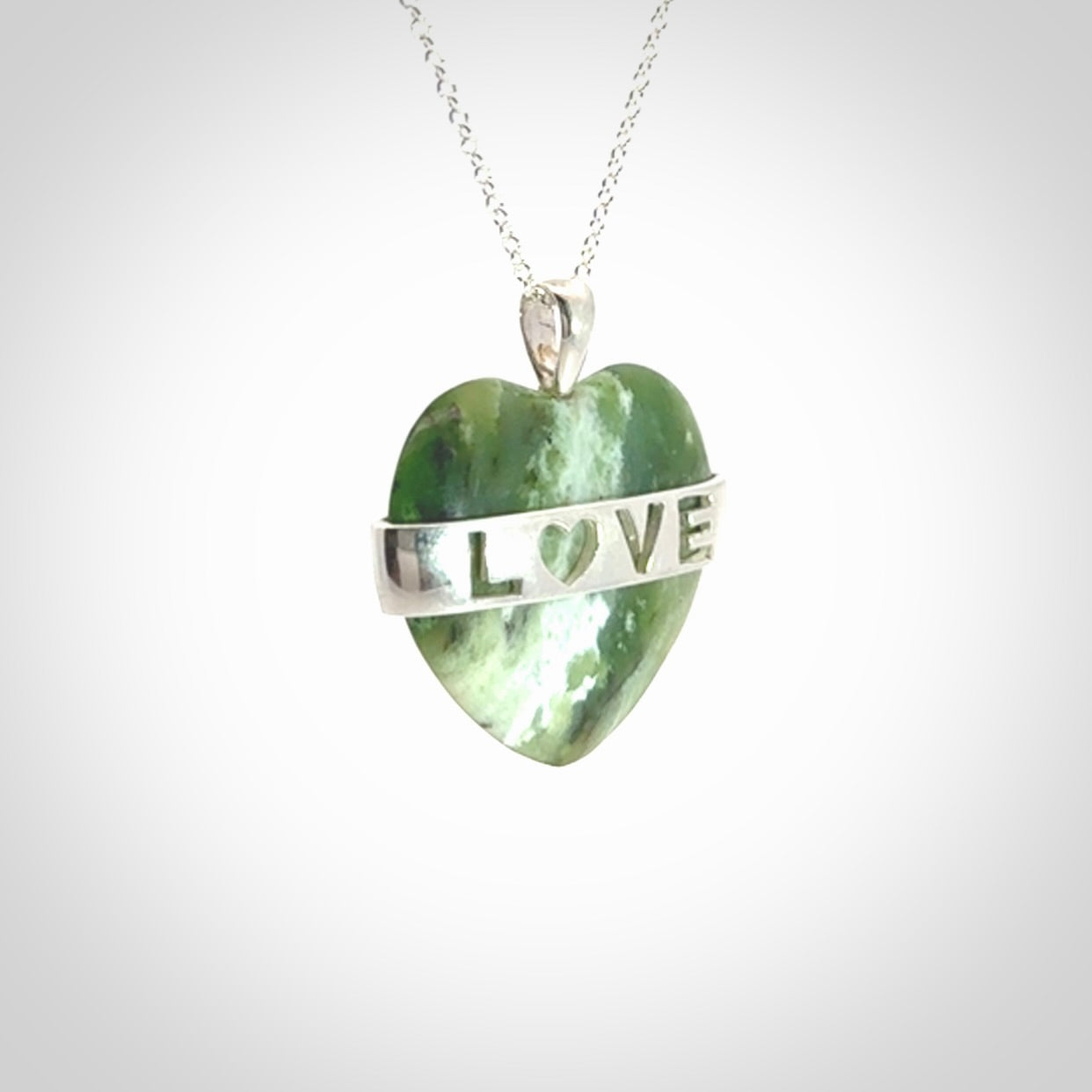 Hand crafted New Zealand jade love heart necklace. This piece has  a sterling silver love written across its' body. This necklace is provided with a sterling silver chain.