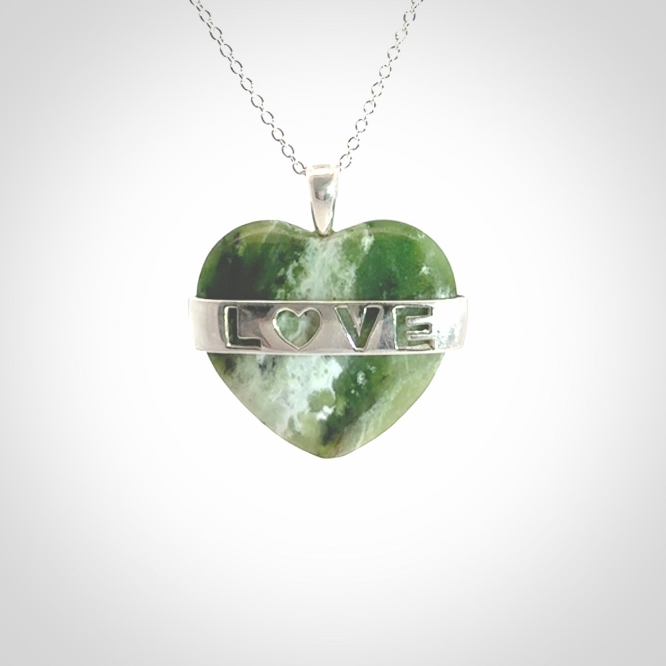 Hand crafted New Zealand jade love heart necklace. This piece has  a sterling silver love written across its' body. This necklace is provided with a sterling silver chain.