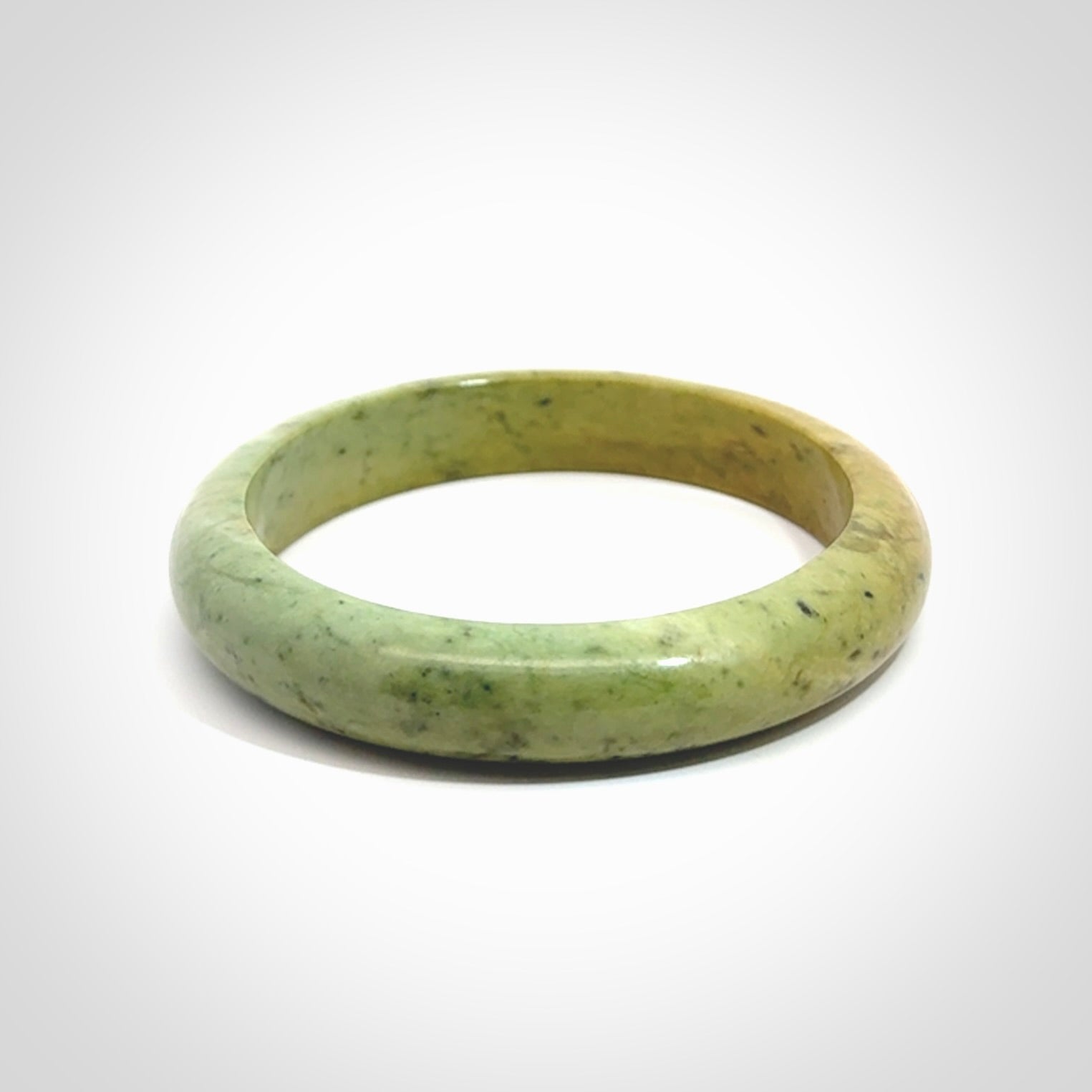 New Zealand flower jade bangle. This is carved from a solid piece of jade and polished to a mirror finish on the outside. The inside is a satin finish. The jade is high grade New Zealand Marsden and is a beautiful coloured stone.