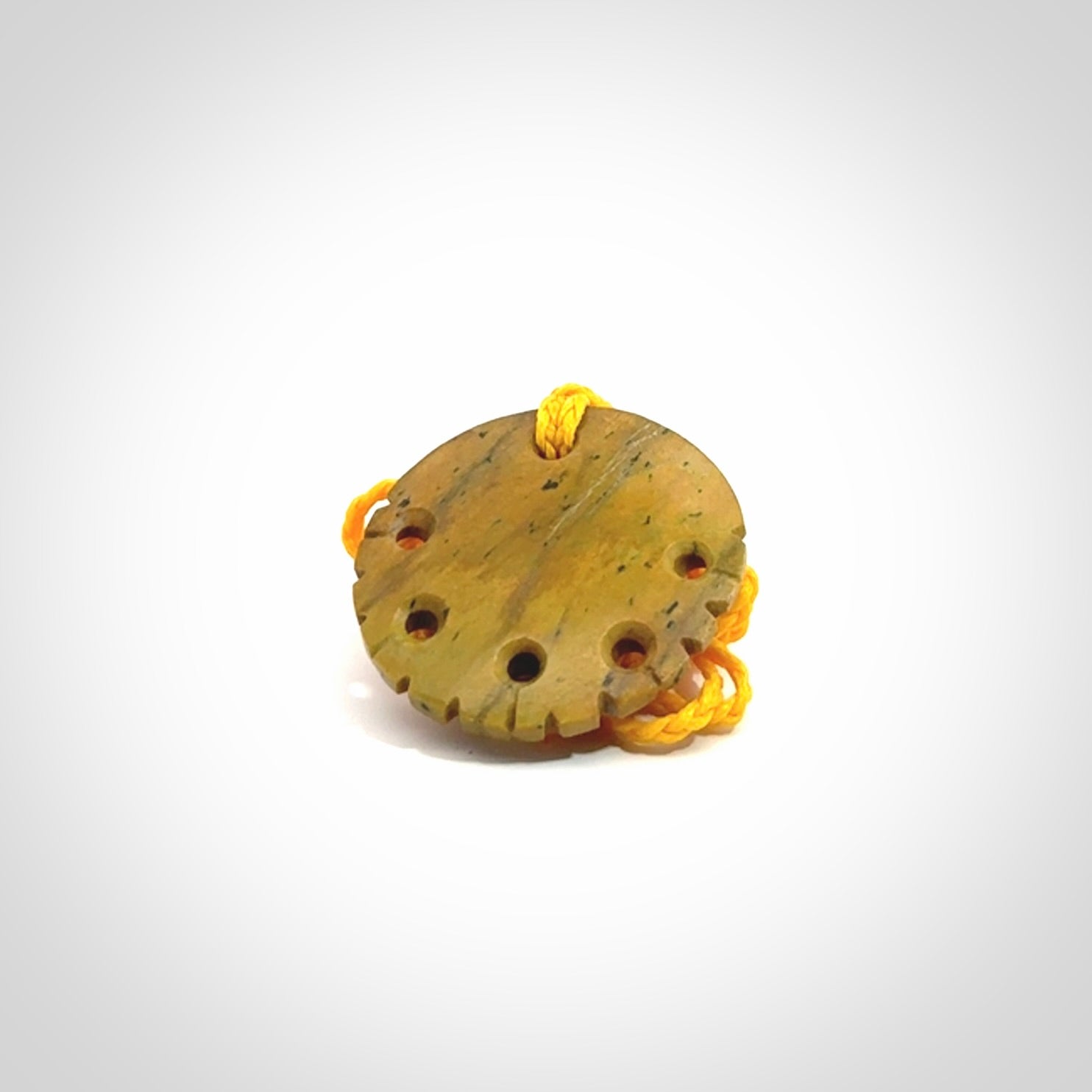 This piece is a smaller sized, oval round, disc pendant. It was carved for us by Alex Sands from a lovely bright and orange piece of New Zealand Flower jade with incredible orange and greens colours at throughout the stone. It is suspended on a yellow coloured braided cord that is length adjustable.