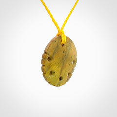 This piece is a smaller sized, oval round, disc pendant. It was carved for us by Alex Sands from a lovely bright and orange piece of New Zealand Flower jade with incredible orange and greens colours at throughout the stone. It is suspended on a yellow coloured braided cord that is length adjustable.