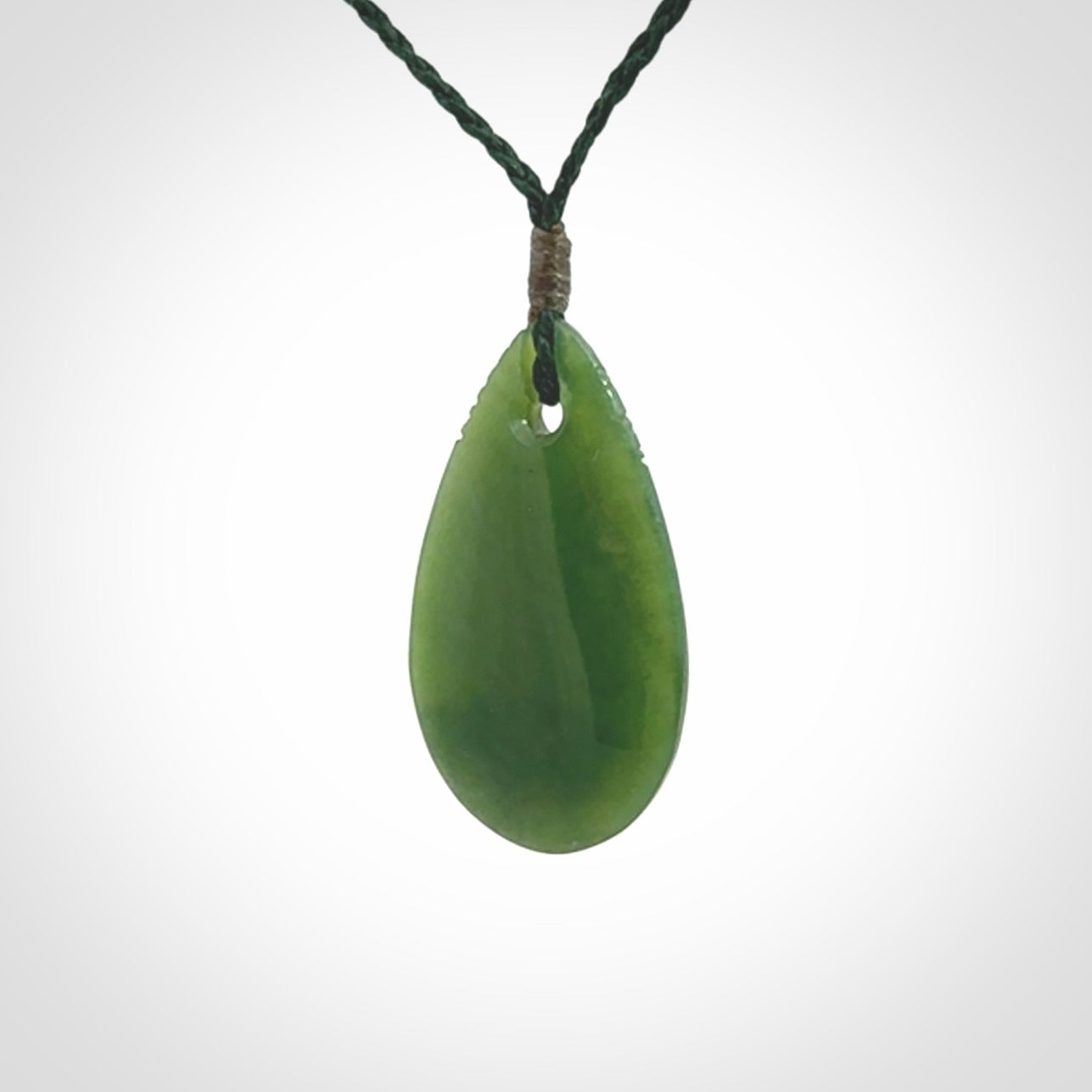 This picture shows a beautiful small sized drop pendant carved in New Zealand Jade, pounamu. It is a lovely semi-translucent green colour, which is glows when held to the light. A gorgeous and very meaningful pendant with an adjustable cord.