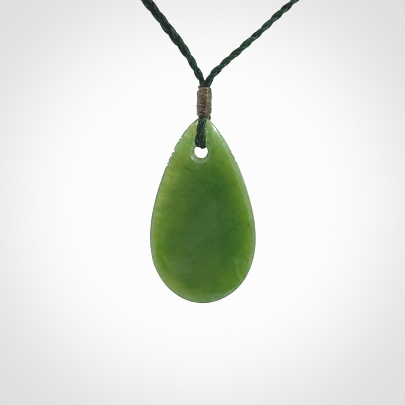 This picture shows a beautiful small sized drop pendant carved in New Zealand Jade, pounamu. It is a lovely semi-translucent green colour, which is glows when held to the light. A gorgeous and very meaningful pendant with an adjustable cord.