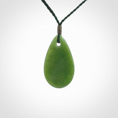 This picture shows a beautiful small sized drop pendant carved in New Zealand Jade, pounamu. It is a lovely semi-translucent green colour, which is glows when held to the light. A gorgeous and very meaningful pendant with an adjustable cord.