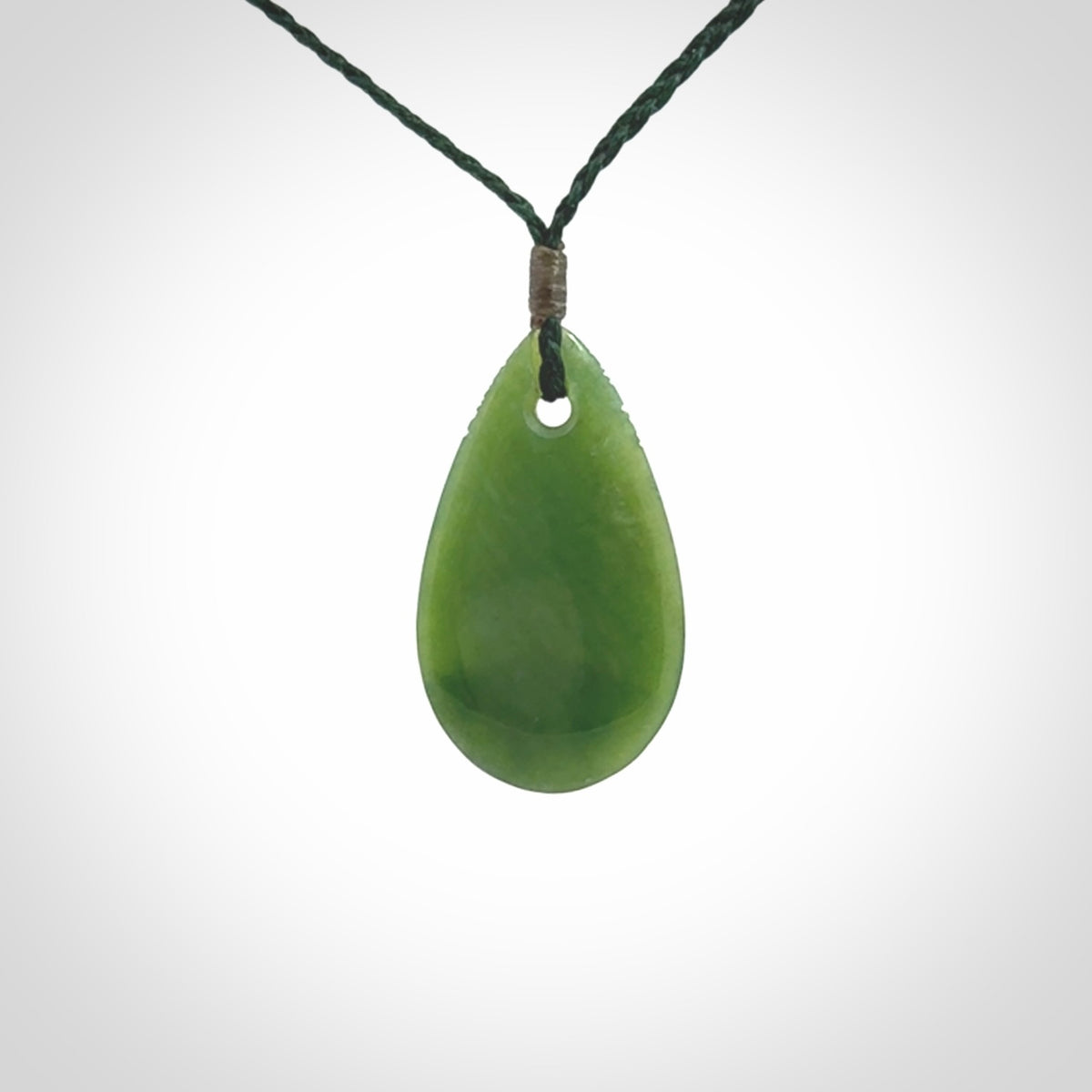 This picture shows a beautiful small sized drop pendant carved in New Zealand Jade, pounamu. It is a lovely semi-translucent green colour, which is glows when held to the light. A gorgeous and very meaningful pendant with an adjustable cord.