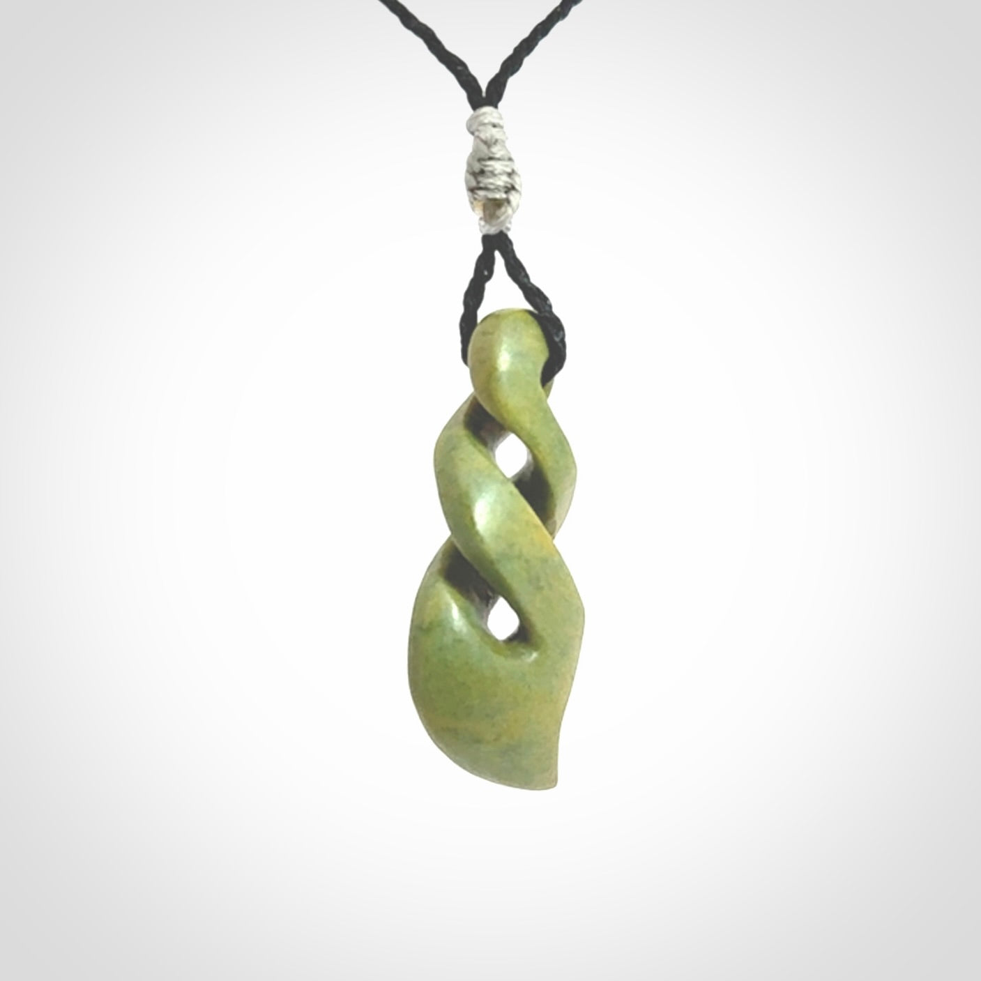Double twist pendant. Hand carved from rare New Zealand flower jade this is a beautiful pounamu pendant. The cord is hand plaited in a black colour and is length adjustable. It has a floret in silver. It is a delicate and very beautiful greenstone pendant. For sale online by NZ Pacific.