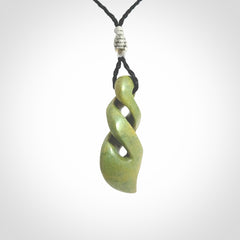 Double twist pendant. Hand carved from rare New Zealand flower jade this is a beautiful pounamu pendant. The cord is hand plaited in a black colour and is length adjustable. It has a floret in silver. It is a delicate and very beautiful greenstone pendant. For sale online by NZ Pacific.