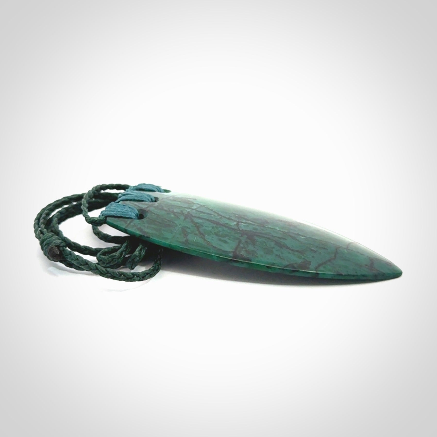 This is a handcrafted aotea stone rei puta pendant.