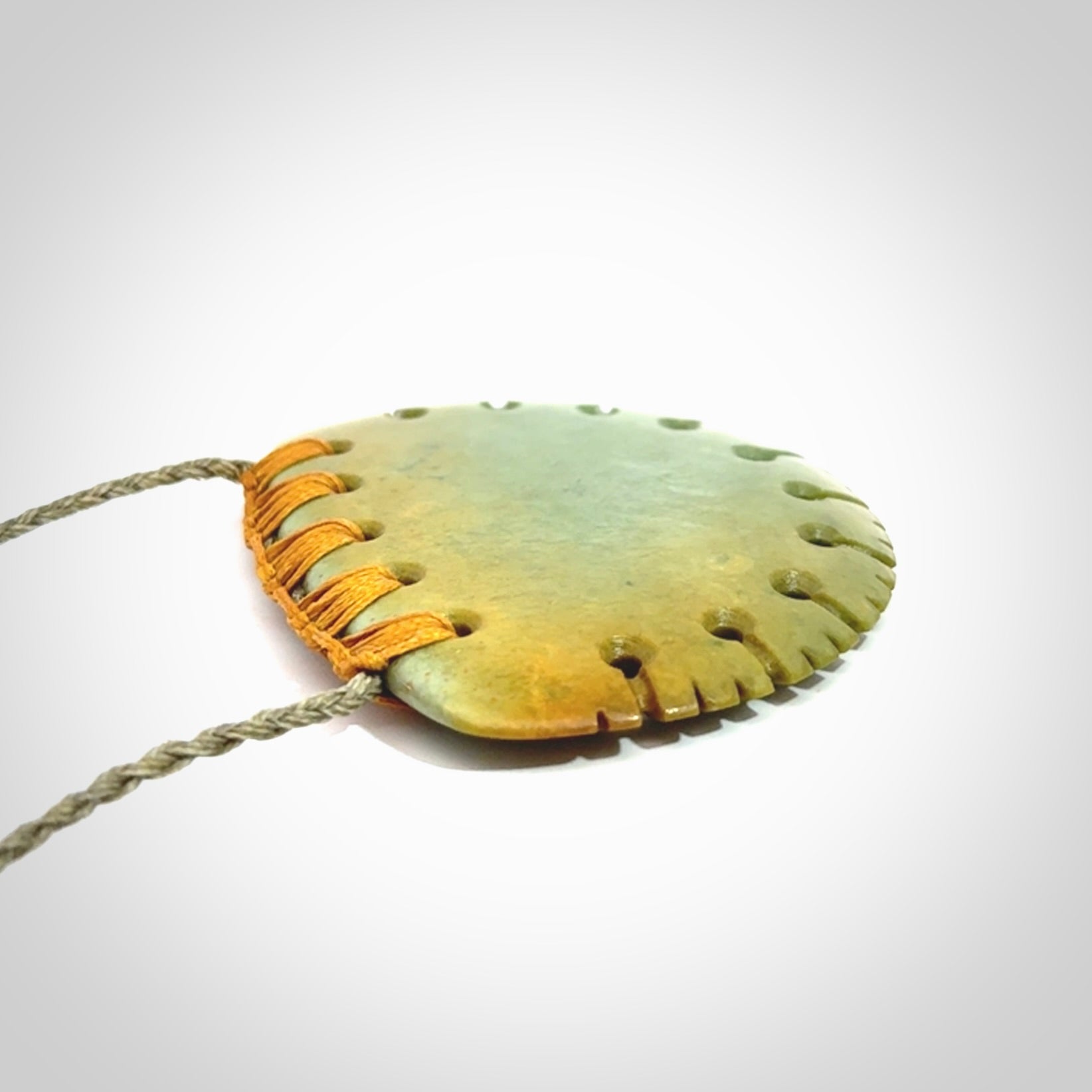 Hand carved New Zealand Flower Jade half-shield pendant.