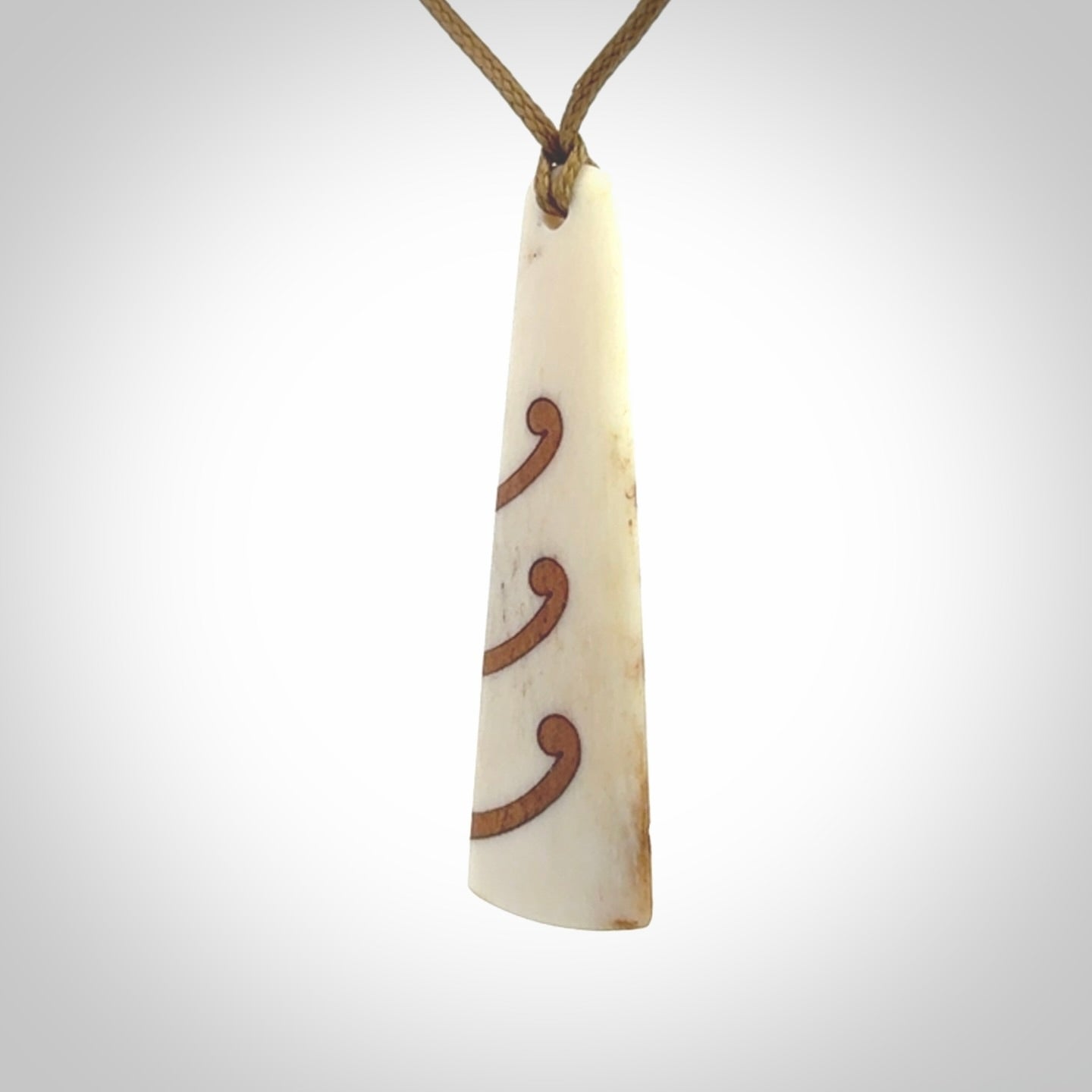 A hand carved, double sided, bone toki with triple koru, intricate pendant. The cord is a black colour and is adjustable.