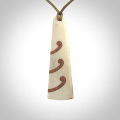 A hand carved, double sided, bone toki with triple koru, intricate pendant. The cord is a black colour and is adjustable.