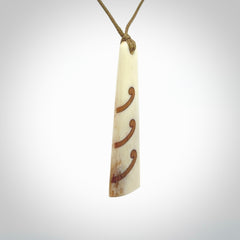 A hand carved, double sided, bone toki with triple koru, intricate pendant. The cord is a black colour and is adjustable.