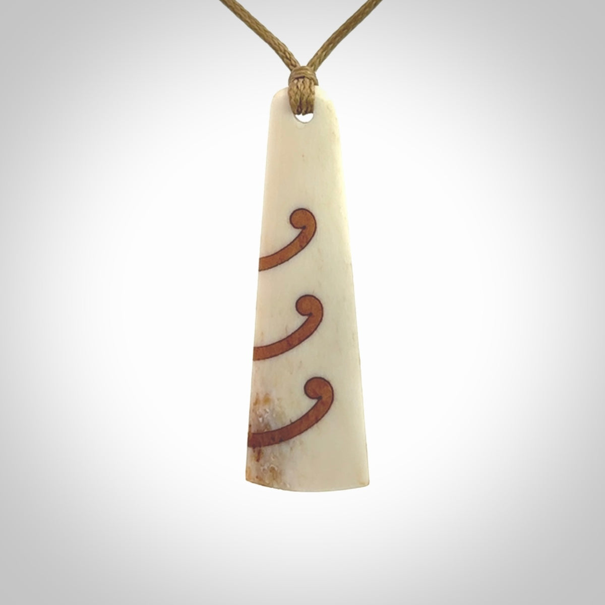 A hand carved, double sided, bone toki with triple koru, intricate pendant. The cord is a black colour and is adjustable.