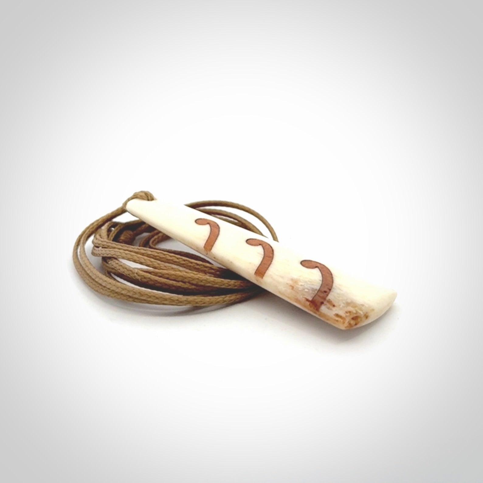 A hand carved, double sided, bone toki with triple koru, intricate pendant. The cord is a black colour and is adjustable.