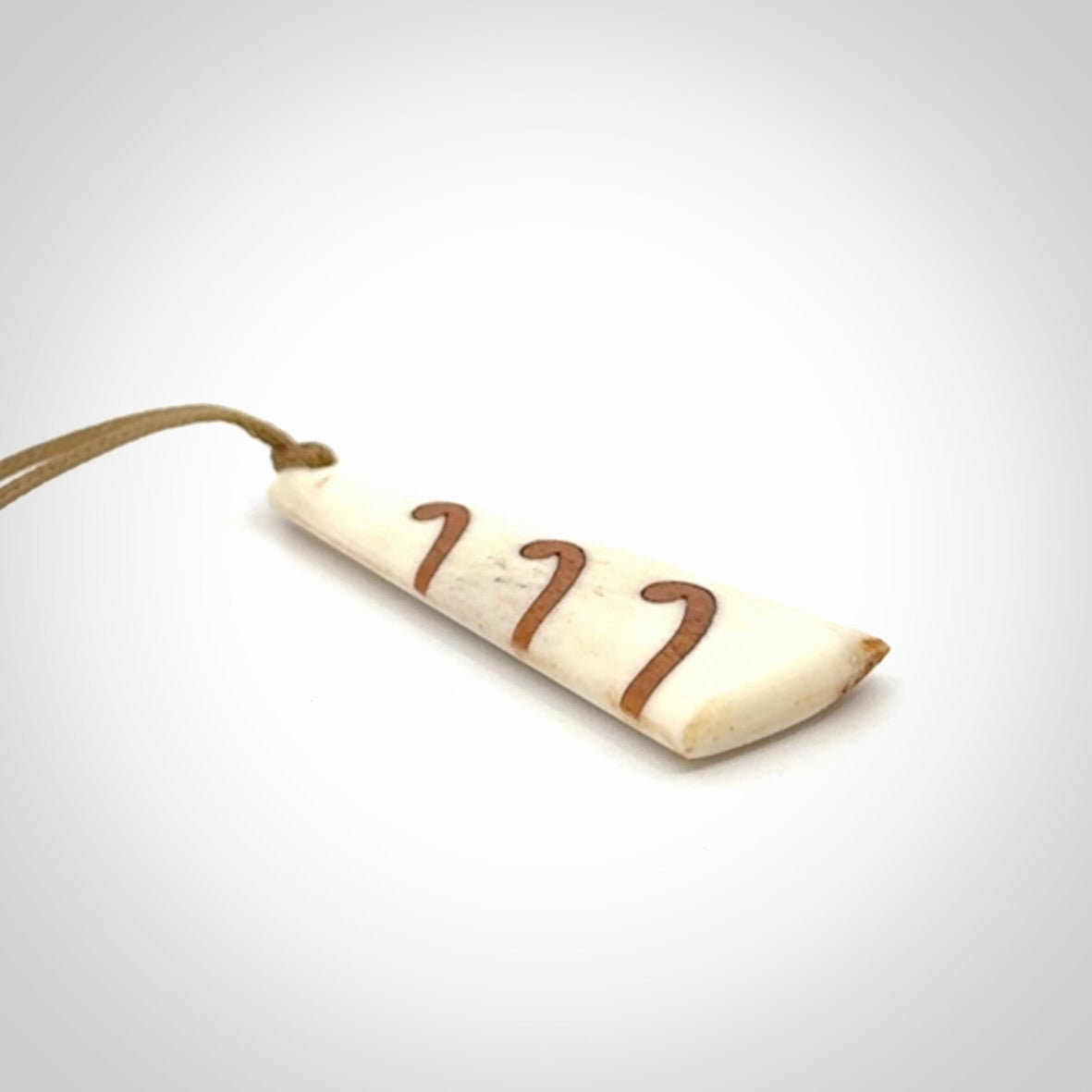 A hand carved, double sided, bone toki with triple koru, intricate pendant. The cord is a black colour and is adjustable.