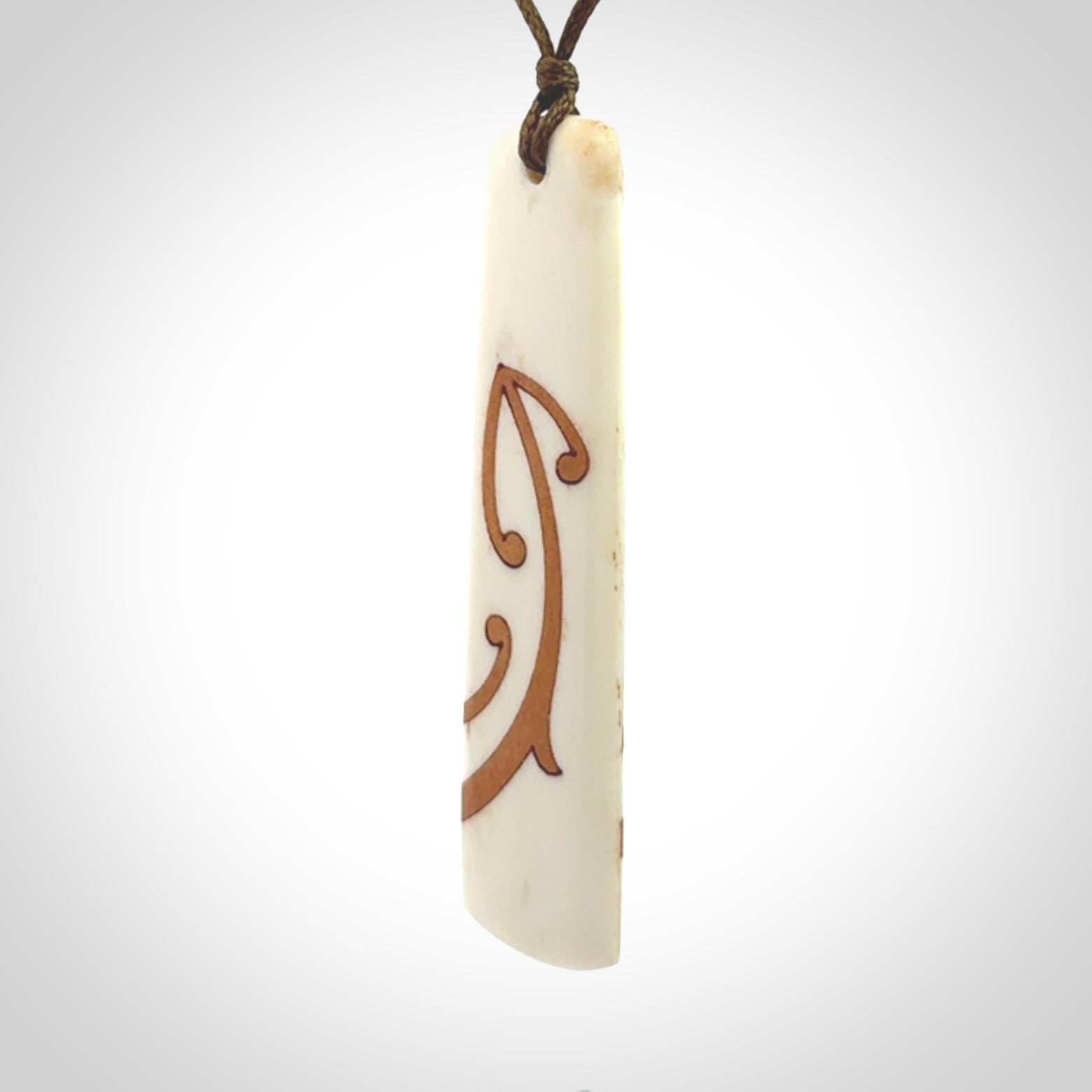 A hand carved, double sided, bone toki with triple koru, intricate pendant. The cord is a marrakesh colour and is adjustable.