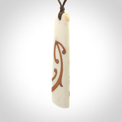 A hand carved, double sided, bone toki with triple koru, intricate pendant. The cord is a marrakesh colour and is adjustable.