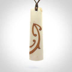 A hand carved, double sided, bone toki with triple koru, intricate pendant. The cord is a marrakesh colour and is adjustable.