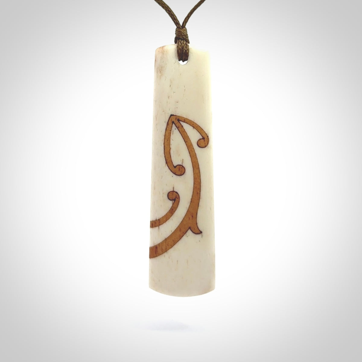 A hand carved, double sided, bone toki with triple koru, intricate pendant. The cord is a marrakesh colour and is adjustable.