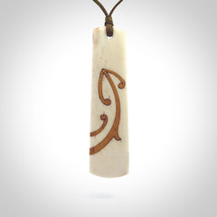 A hand carved, double sided, bone toki with triple koru, intricate pendant. The cord is a marrakesh colour and is adjustable.