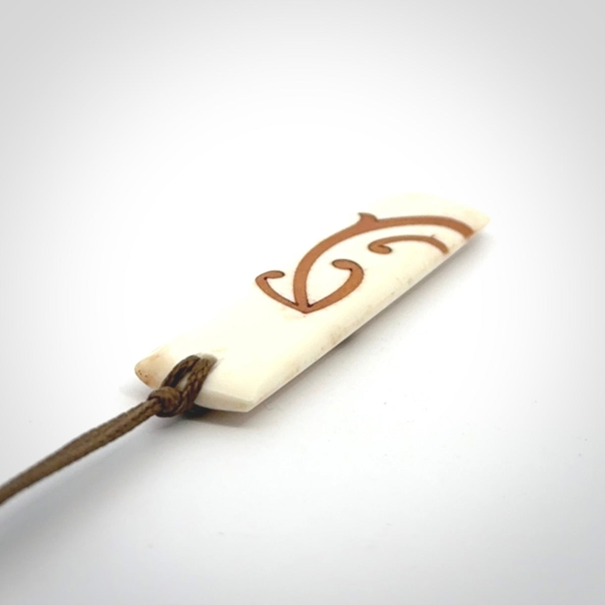 A hand carved, double sided, bone toki with triple koru, intricate pendant. The cord is a marrakesh colour and is adjustable.