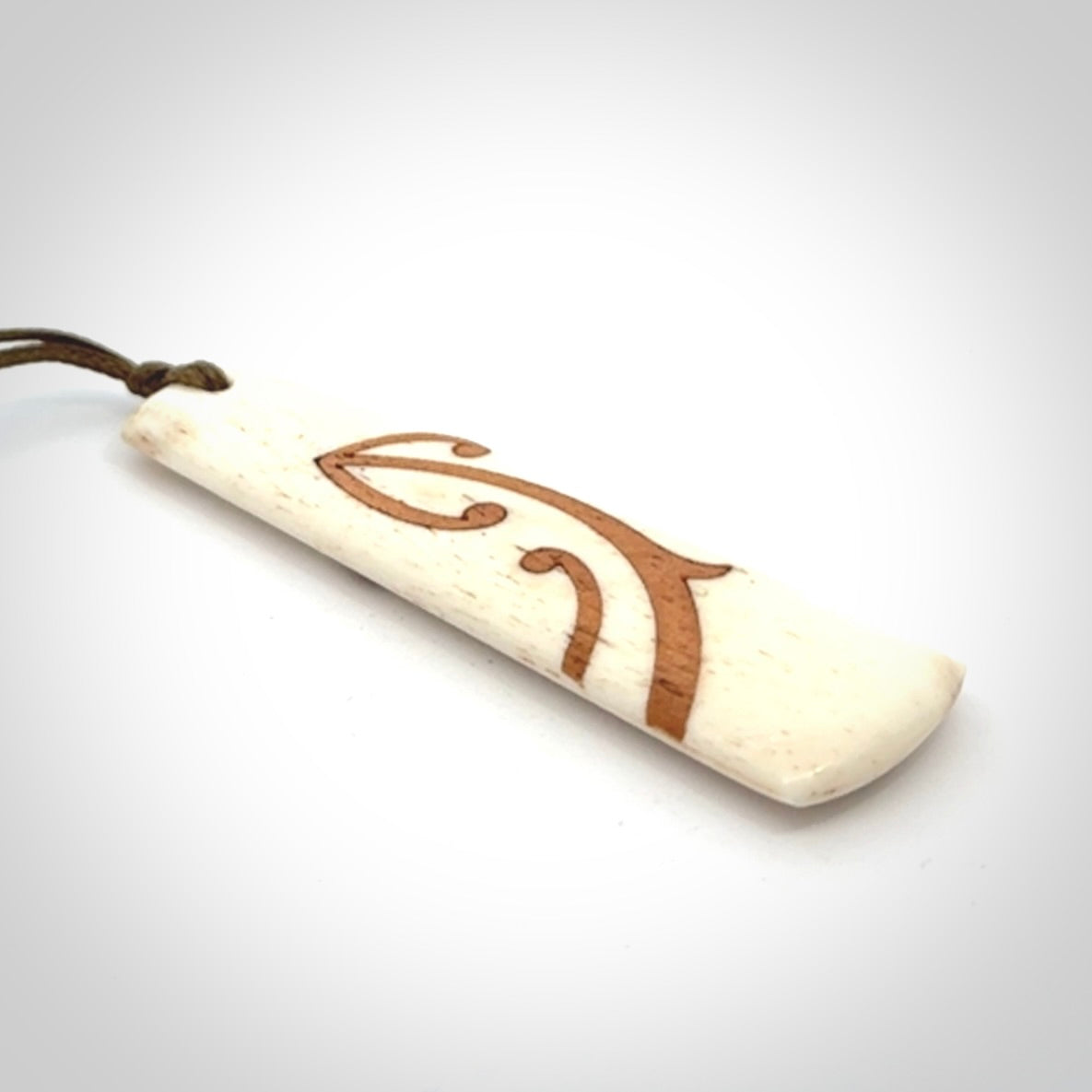 A hand carved, double sided, bone toki with triple koru, intricate pendant. The cord is a marrakesh colour and is adjustable.