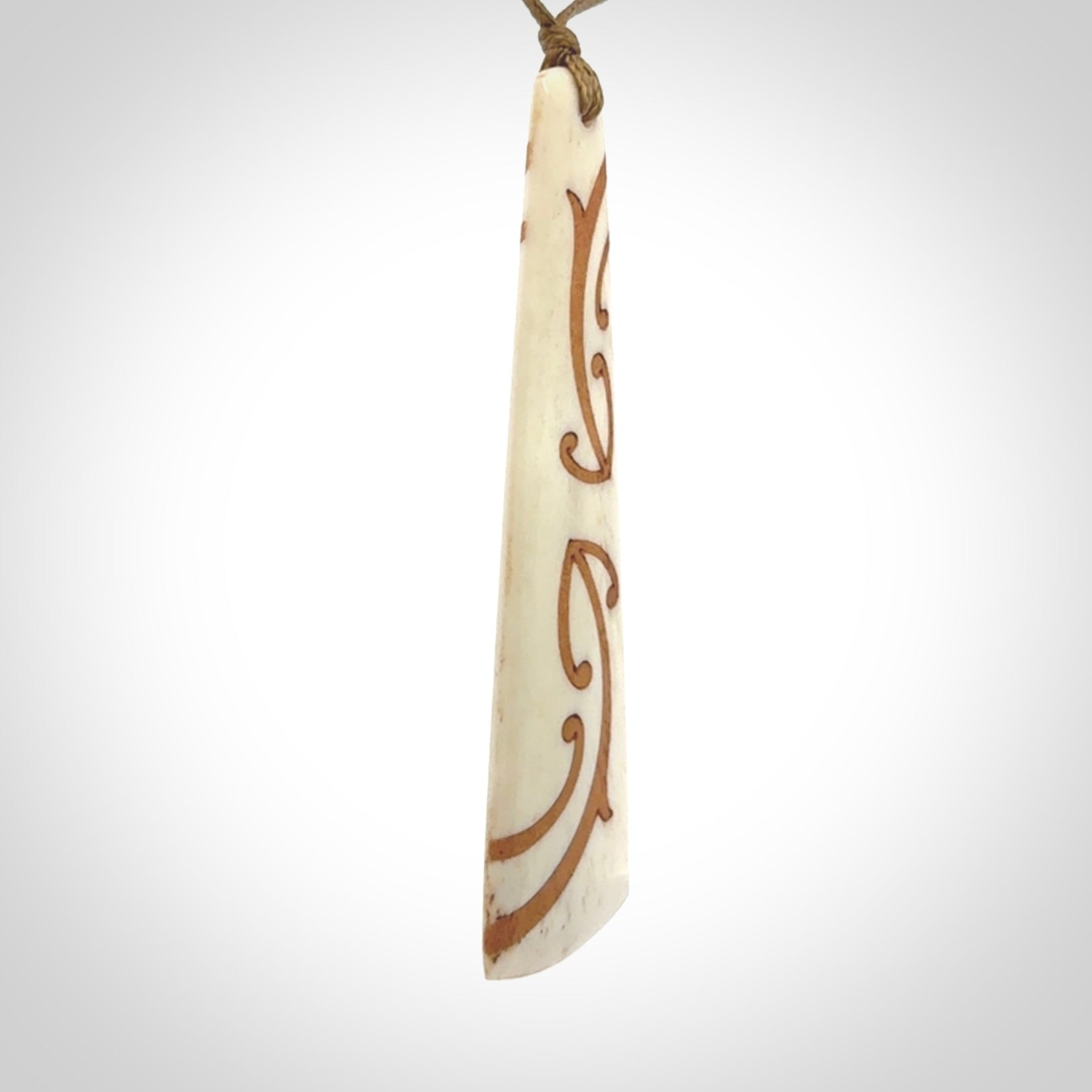 A hand carved, double sided, bone toki with triple koru, intricate pendant. The cord is a camel colour and is adjustable.